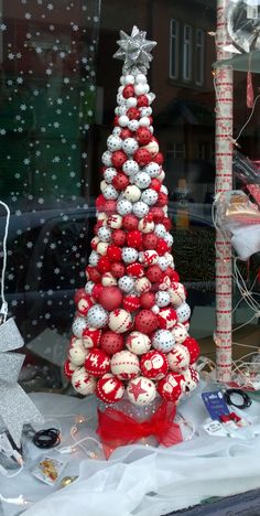 a red and white christmas tree sitting on top of a table next to a window