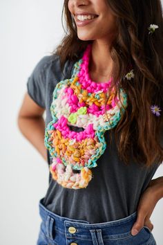 a woman wearing a multicolored crocheted scarf with flowers in her hair