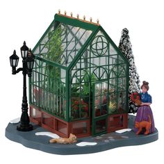 a miniature model of a green house with a woman and dog in front of it