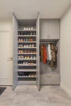 a walk in closet filled with lots of shoes and coats hanging on the wall next to an open door