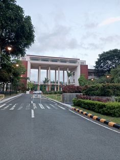 an empty street in front of a large building with columns and pillars on each side