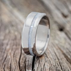 a wedding band with two silver rings on top of a piece of wood, sitting on a wooden surface