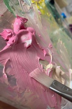 a paintbrush is being used to make pink and white icing on a piece of art