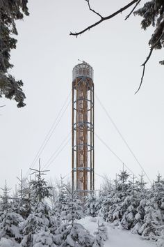 a tall tower sitting in the middle of a forest covered in snow