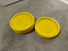 two yellow frisbees sitting on the floor next to each other