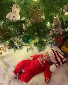 a baby is laying under the christmas tree