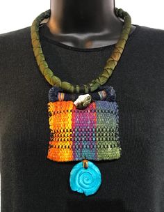 a multicolored necklace on a mannequin neck with a blue flower in the center