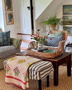 a living room filled with furniture next to a stair case and potted plant on top of a coffee table