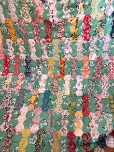 an old quilt is being displayed on a tablecloth with many different colors and patterns