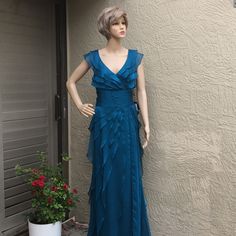 a mannequin dressed in a blue dress next to a flower pot and door