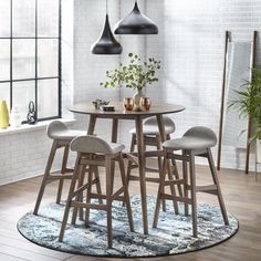 a round table with two stools in front of it and a rug on the floor