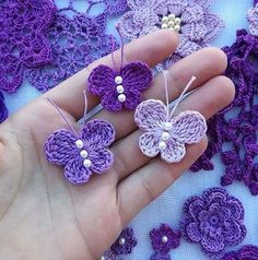 three crocheted flowers are being held in someone's hand with pearls on them