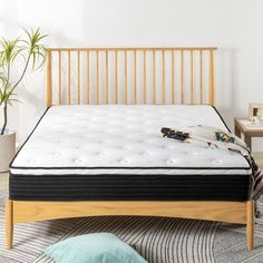 a bed with a wooden headboard and mattress on the floor next to a potted plant