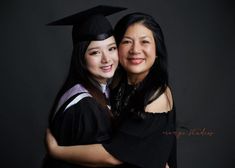 two women in graduation gowns hugging each other