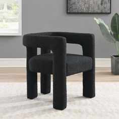 a black chair sitting on top of a rug next to a potted plant