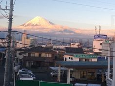 a view of a mountain in the distance with buildings and cars parked on the street