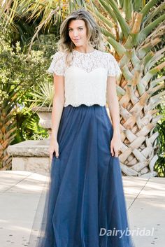 a woman wearing a blue and white dress standing in front of a palm tree with her hand on her hip