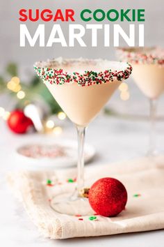 two martini glasses with sprinkles and a red ornament on the side