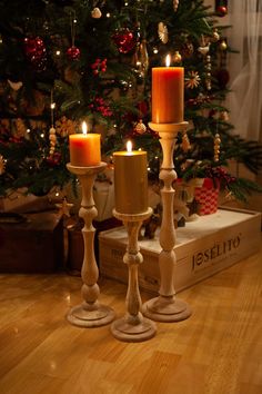 two candles are lit in front of a christmas tree