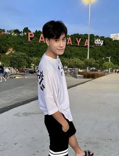 a young man riding a skateboard on top of a cement ground next to a park