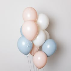 a bunch of balloons that are on top of each other in front of a white wall