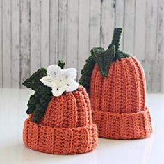 two knitted pumpkins sitting on top of a white table