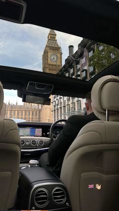 two people sitting in the back seat of a car with big ben in the background