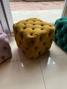 three different colored stools sitting in front of a window