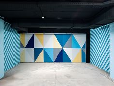 an empty parking garage with blue and yellow geometric wallpaper on the walls behind it