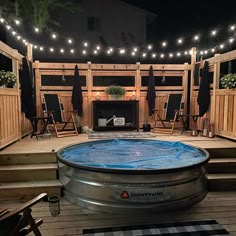 an above ground hot tub in the middle of a deck with lights strung over it