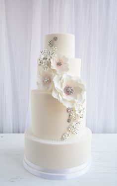 a three tiered white wedding cake with flowers on top