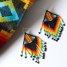 Hand woven by indigenous Embera Chami artisans, these seed bead earrings represent a piece of Colombian culture, fusing modern designs with ancient tribal craftsmanship. The Embera Chami tribe are known for their intricate and colorful bead work and these earrings do not disappoint. Each pair features beautiful bead detailing in a unique FOSTERIE exclusive small batch pattern. Materials: Seed beadsSize: Approximately 3 inches from top of hook, 1.5 inch wide Modern Multicolor Dangle Jewelry, Artisan Black Dangle Earrings, Artisan Black Jewelry With Ear Wire, Artisan Multicolor Jewelry With Black Beads, Modern Handmade Rainbow Jewelry, Modern Colorful Handmade Jewelry, Artisan Black Beaded Drop Earrings, Black Artisan Earrings, Multicolor Handwoven Teardrop Earrings