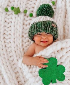 a baby wearing a green hat and holding a shamrock