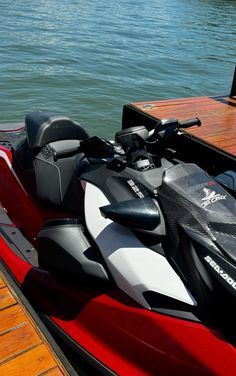 a red and black jet ski sitting on top of a wooden dock