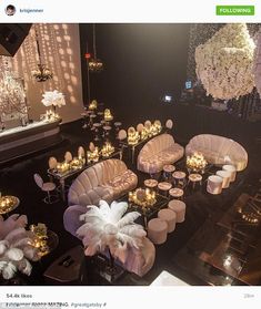 a room filled with lots of white couches and tables covered in candles next to chandeliers