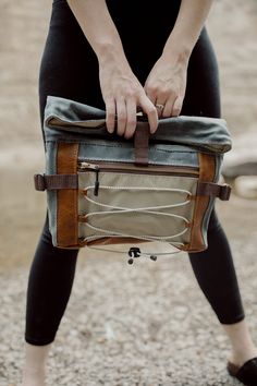 "The Denver Roll Top has it all; ample space and storage, ultimate comfort and multiple carrying options. This bag, made from waxed canvas, leather and waterproof ripstop, features cushioned hip flaps to wear around your waist or across your chest/back. It comes with a detachable, adjustable wide webbing strap to wear the bag crossbody or over the shoulder. The large front zipper pocket features shock cording to carry any additional items, like a layering shirt for hiking or a pair of gloves. Attach a carabiner to the cording and bring along doggie bags on your walk. Ripstop lining is waterproof, lightweight and super durable. Inside, you'll find two slip pockets. The Denver Roll Top has a leather base for added durability. Dimensions: 15\" wide 13.5\" tall (unrolled) 9.5\" tall (rolled) 3 Outdoor Leather Shoulder Saddle Bag, Rugged Bag With Waxed Finish For Outdoor Activities, Rugged Waxed Canvas Bag For Outdoor Activities, Coated Canvas Bags For Outdoor Activities, Outdoor Shoulder Bag With Waxed Finish, Leather Saddle Bag With Adjustable Strap For Outdoor, Functional Waxed Canvas Bags For Outdoor Activities, Outdoor Waxed Finish Shoulder Bag Backpack, Outdoor Waxed Finish Crossbody Shoulder Bag