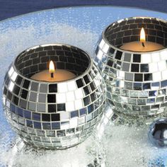 two disco ball candles sitting on top of a blue table next to a candle holder