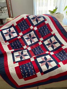 a red, white and blue quilt on a couch in front of a potted plant