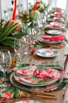 the table is set with flamingos and tropical leaves on it, including pink flowers