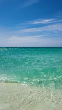 an ocean view with clear blue skies and white sand on the beach, as seen from the water's edge