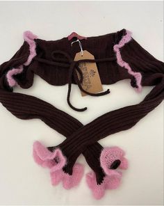 a knitted scarf with pink and brown trims on the bottom, attached to a string