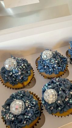 cupcakes with blue frosting and decorations in a box