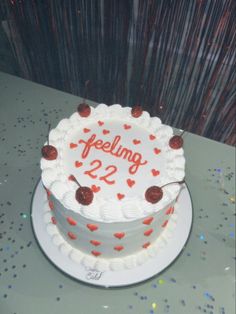 a white cake with red hearts and the number 22 on it is sitting on a table