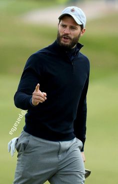 a man with a baseball cap on giving the thumbs up while holding a golf club