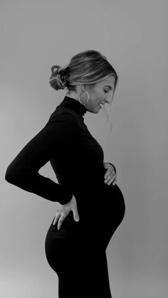 a pregnant woman poses for a black and white photo with her hands on her hips