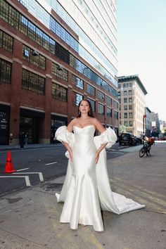 a woman in a white dress standing on the street