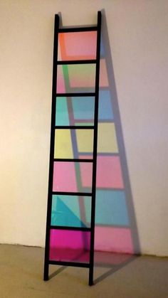 a ladder leaning against a wall with multicolored squares on it's sides