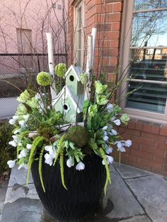 a planter with candles and flowers in front of a house