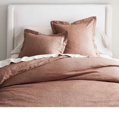 a bed with brown linens and pillows on it's headboard in a bedroom