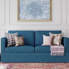 a blue couch sitting in front of a painting on the wall next to a rug